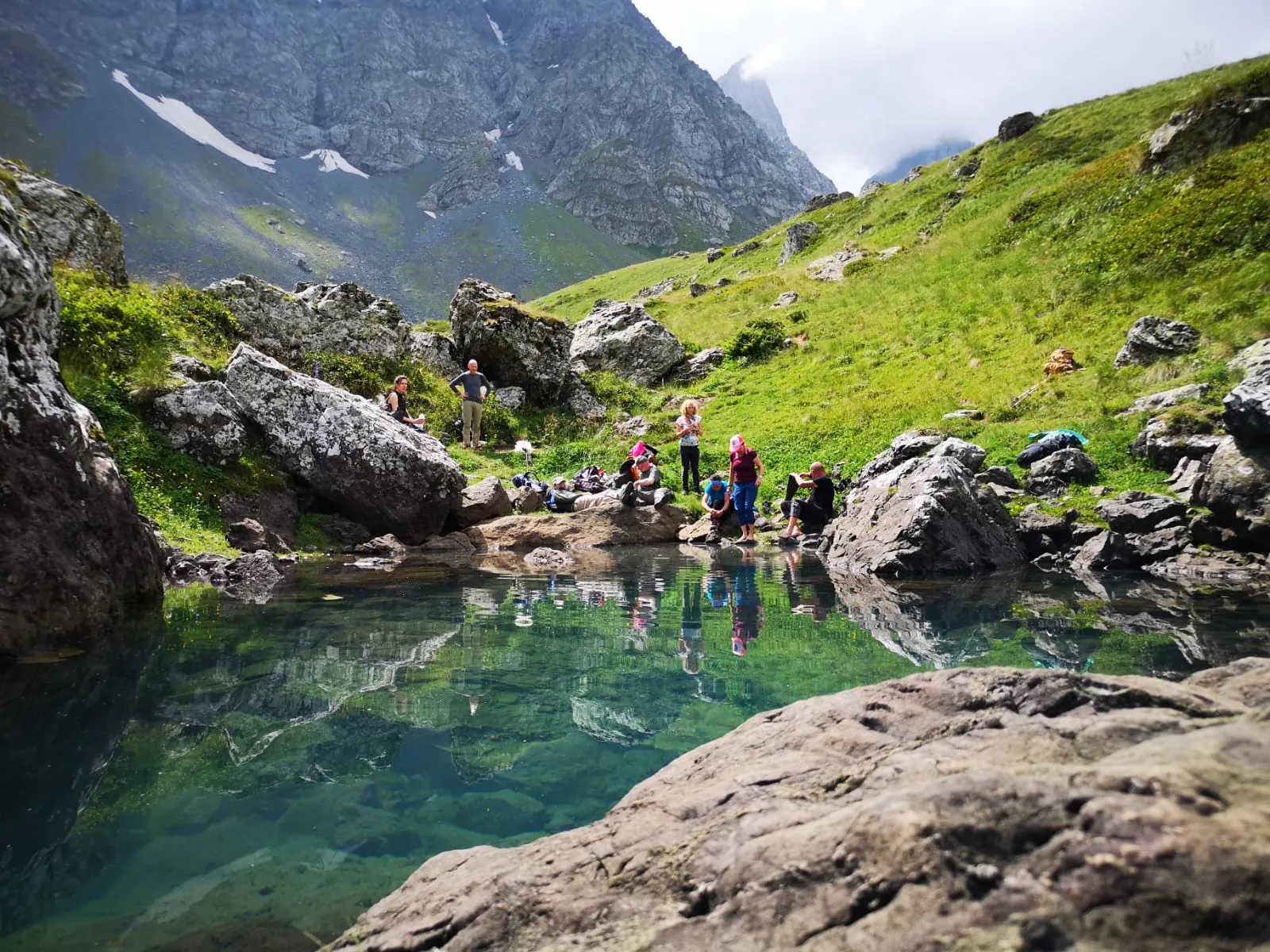 Hikers resting beside an emerald mountain lake
